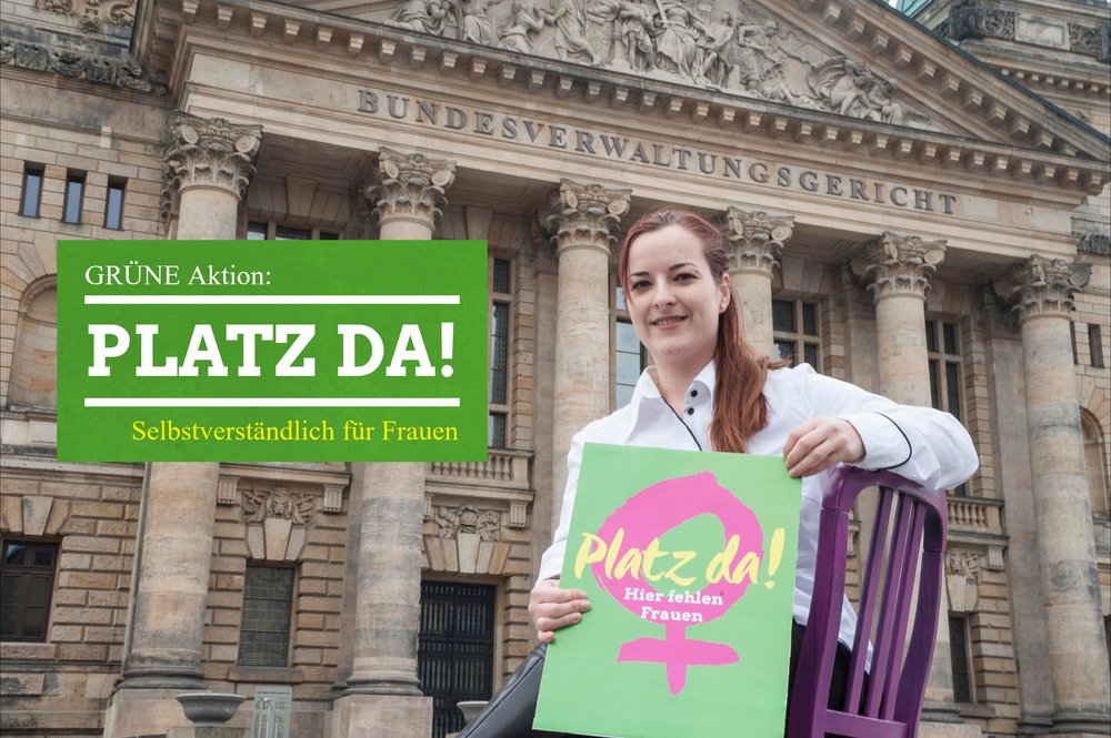 Das Foto zeigt eine junge Frau, die auf einem pinken Stuhl vor dem Leipziger Bundesverwaltungsgericht sitzt. Sie hält ein Schild in der Hand auf dem steht: Platz da! Hier fehlen Frauen! Dazu gibt es ein grün hinterlegtes Textfeld auf welchem steht: GRÜNE Aktion: Platz da! Selbstverständlich für Frauen!