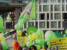 Auf dem Bild sind viele grüne Ballons und Flaggen zu sehen, die über den Köpen Demonstrierender fliegen. Es ist ein Panoramabild, sodass die Demonstrierenden nur durch das zeigen der Haare und Mützen zu sehen sind. Der Rest ist Himmel.