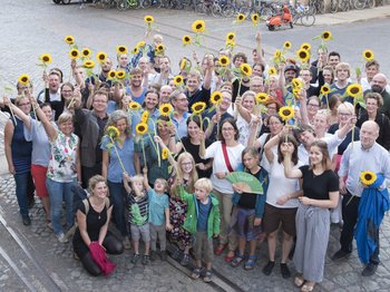 Auf dem Foto ist eine Gruppe von rund 60 Menschen mit Sonnenblumen zu sehen.