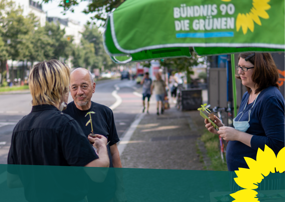 Drei Menschen unterhalten sich am GRÜNEN-Infostand