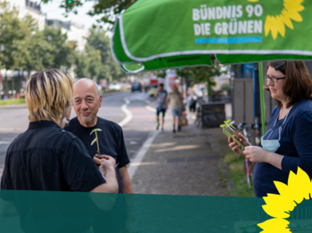 Drei Menschen unterhalten sich am GRÜNEN-Infostand