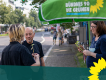 Drei Menschen unterhalten sich am GRÜNEN-Infostand